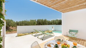 An outdoor dining area with a table set for two, chairs, and a view of a pool and trees. - Masseria Pensato SUITE CARRUBO (Fasano)