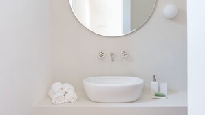 A bathroom with a round mirror, a white sink, and a towel rack. - Masseria Pensato SUITE CARRUBO (Fasano)
