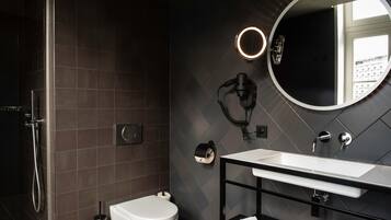 Un baño moderno con ducha, inodoro y tocador con espejo y lavabo.