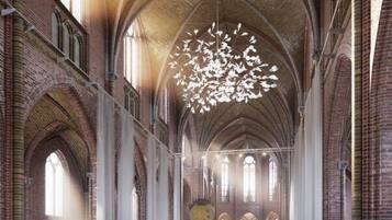 A spacious interior with high ceilings, arched windows, and a modern chandelier.