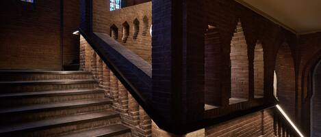 A staircase with brick walls and a stained glass window.