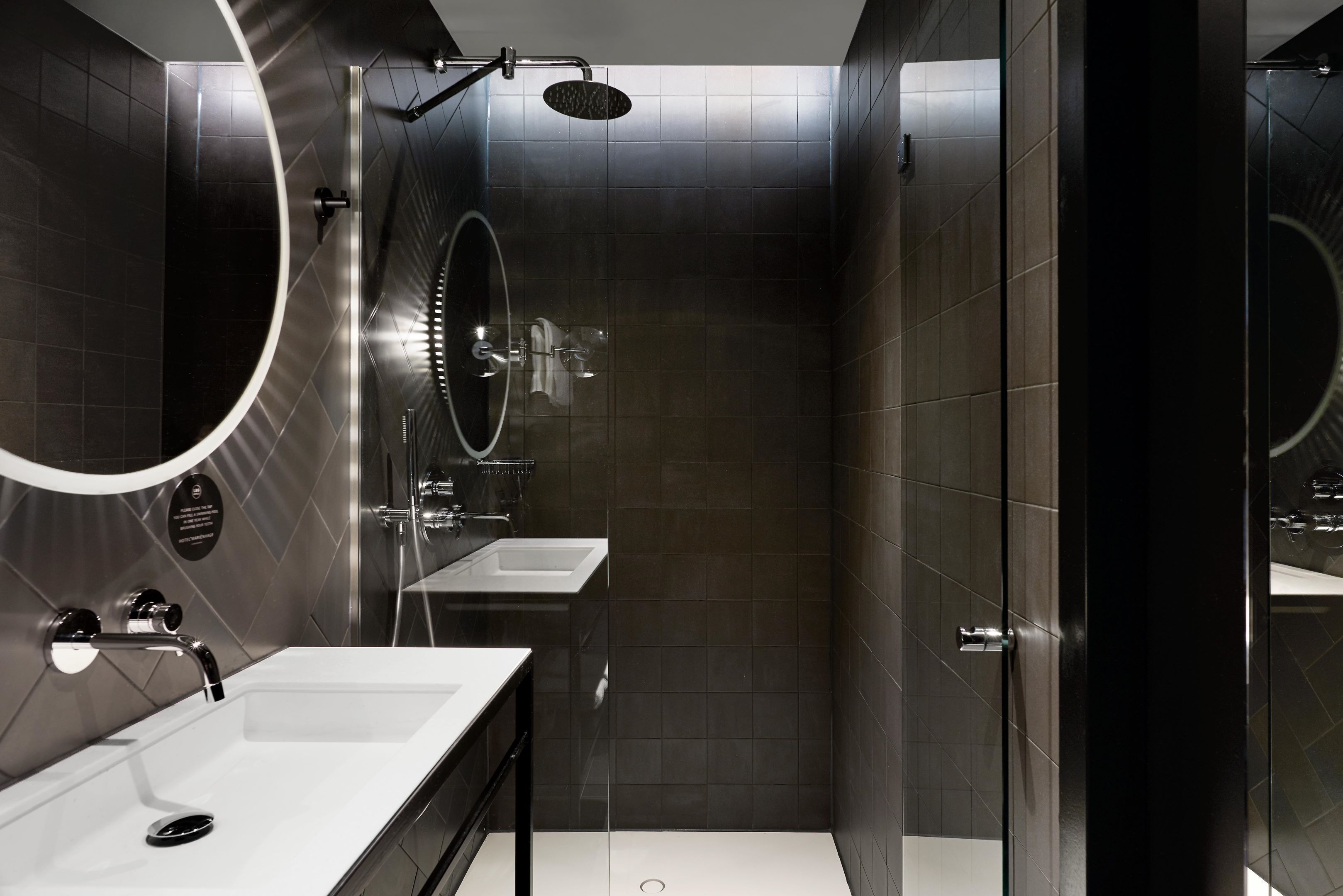 A modern bathroom with a large mirror, a shower, and a sink.