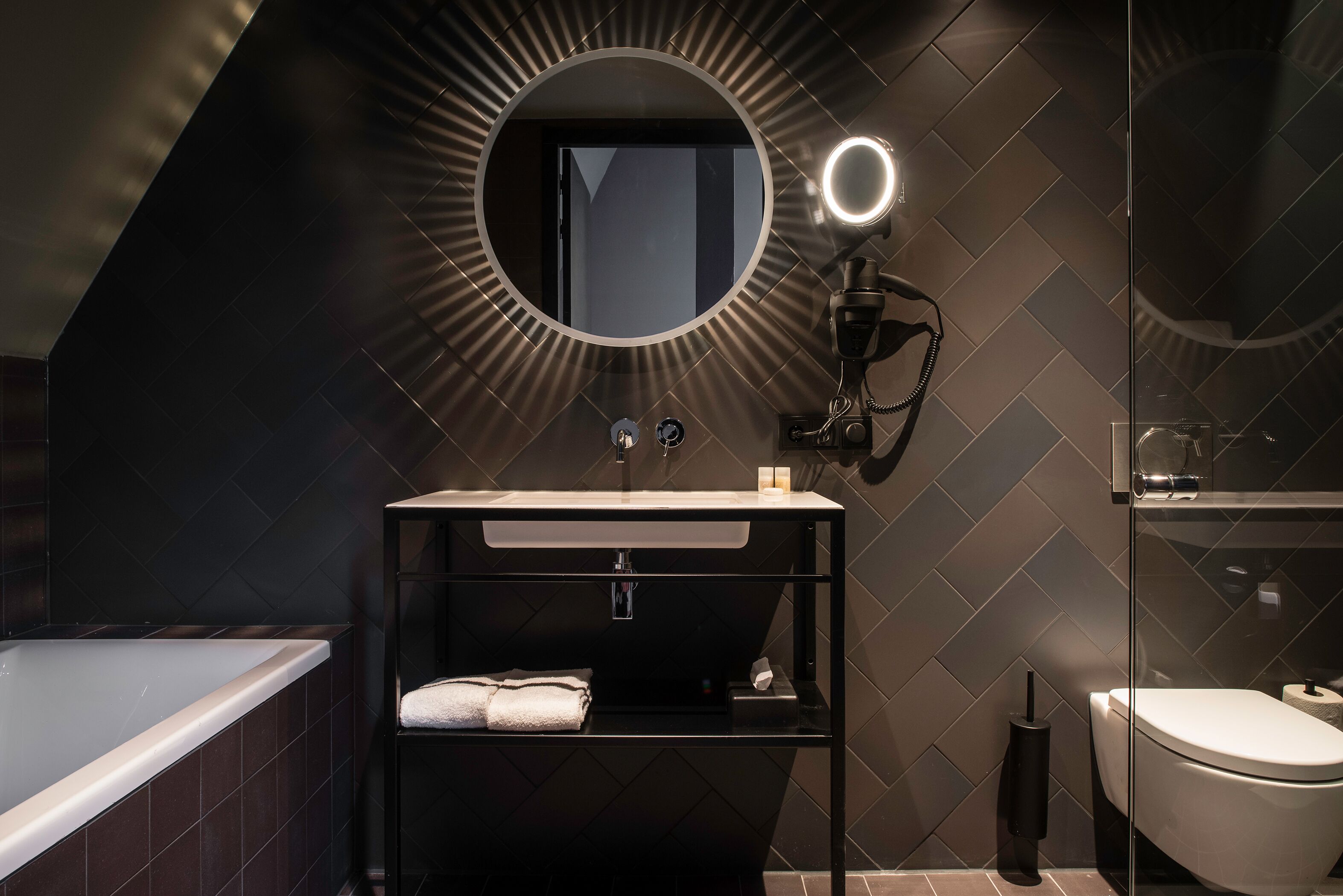 A modern bathroom with a freestanding bathtub, a vanity with a mirror, and a toilet.