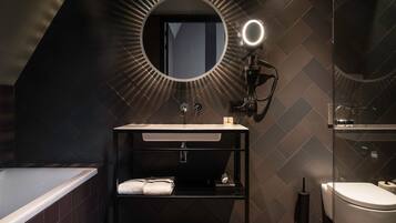 A modern bathroom with a freestanding bathtub, a vanity with a mirror, and a toilet.