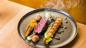 A plate of food with various items including a piece of meat, vegetables, and a roll.