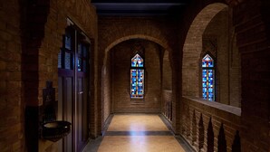 A corridor with brick walls, a polished floor, and two stained glass windows. - Mariënhage Boutique Hotel (Eindhoven)