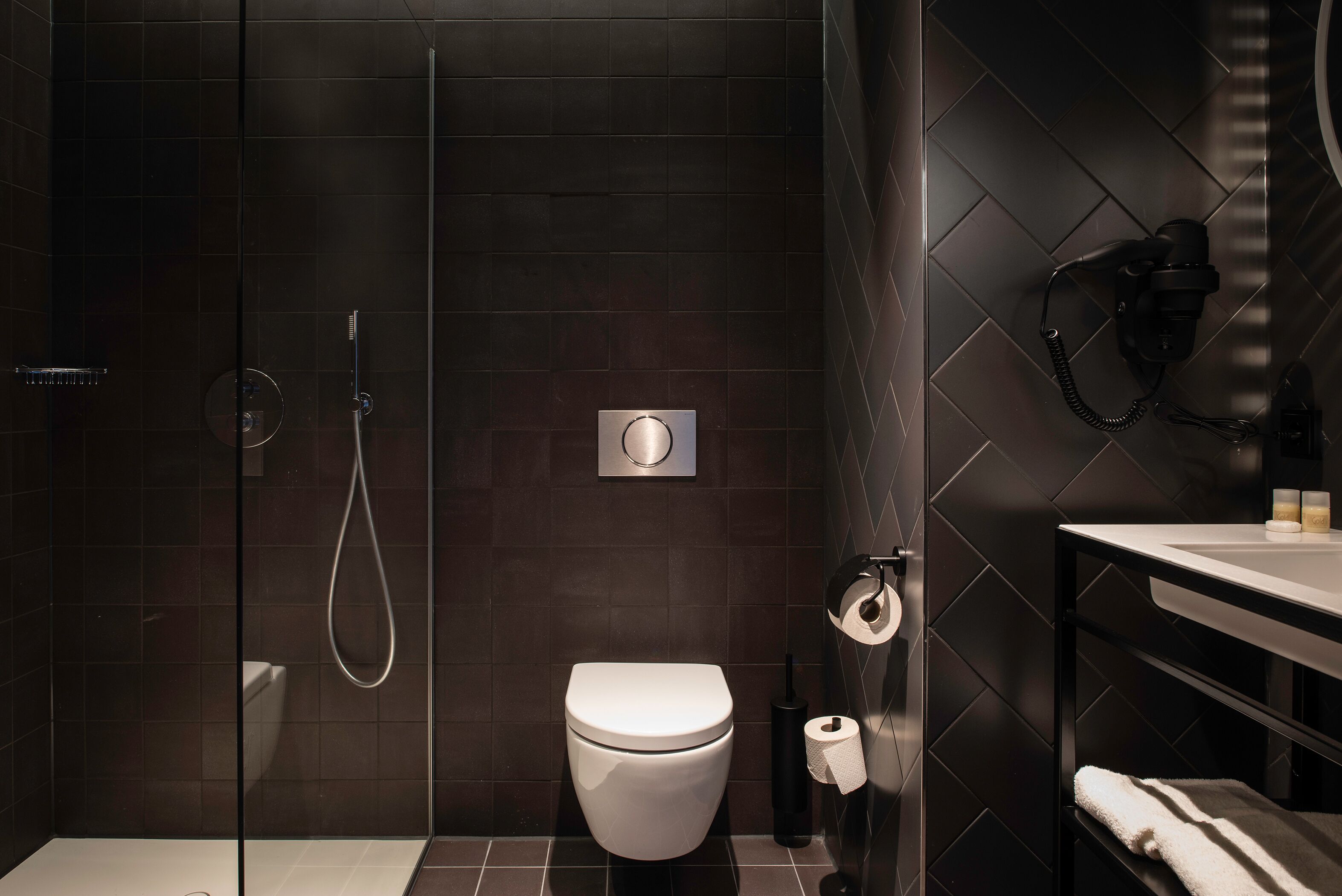 Ein modernes Badezimmer mit einer gläsernen Duschkabine, einer weißen Toilette und einem Handtuchhalter.