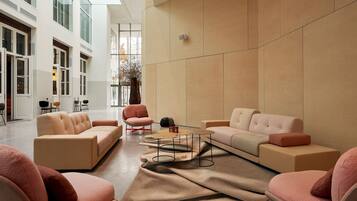 Een modern interieur met banken en stoelen rond een centrale salontafel, grote ramen en een minimalistisch ontwerp.