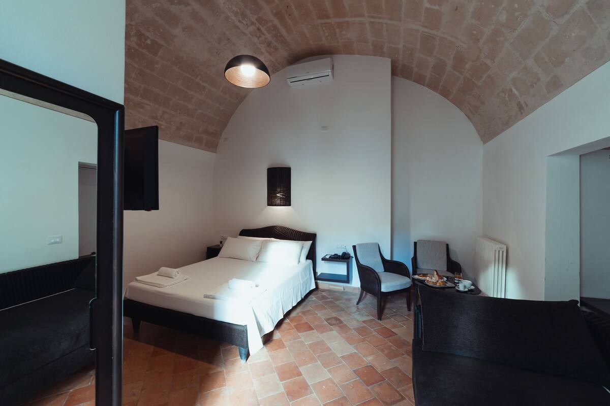 Quarto com cama, uma cadeira, uma mesa com café da manhã e uma televisão.