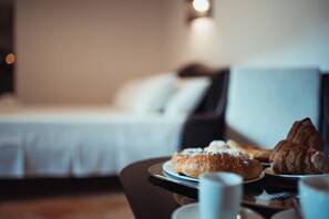 A hotel room with a bed in the background, a table with pastries and a cup in the foreground. - Gradelle San Nicola (Matera)
