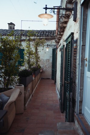 A narrow courtyard with a tiled floor, a sofa, potted plants, and a hanging light fixture. - Gradelle San Nicola (Matera)