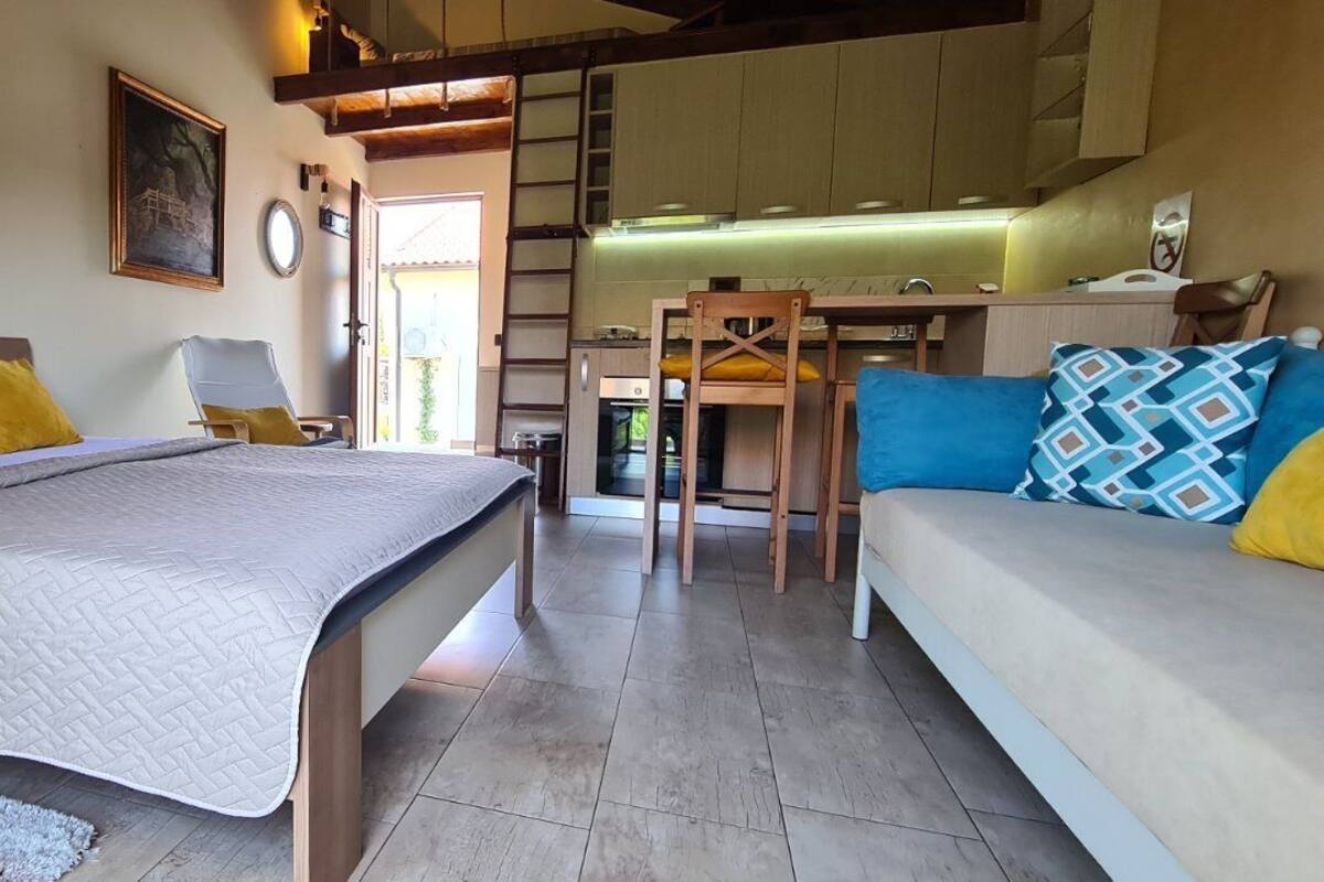 Quarto com cama, mesas de cabeceira, sofá e área de jantar com cadeiras e mesa.