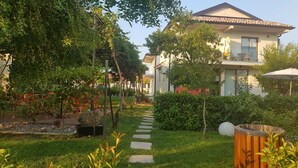 A well-maintained garden with a stone pathway leading to a house with a tiled roof. - Apartments Aerodrom (Podgorica)
