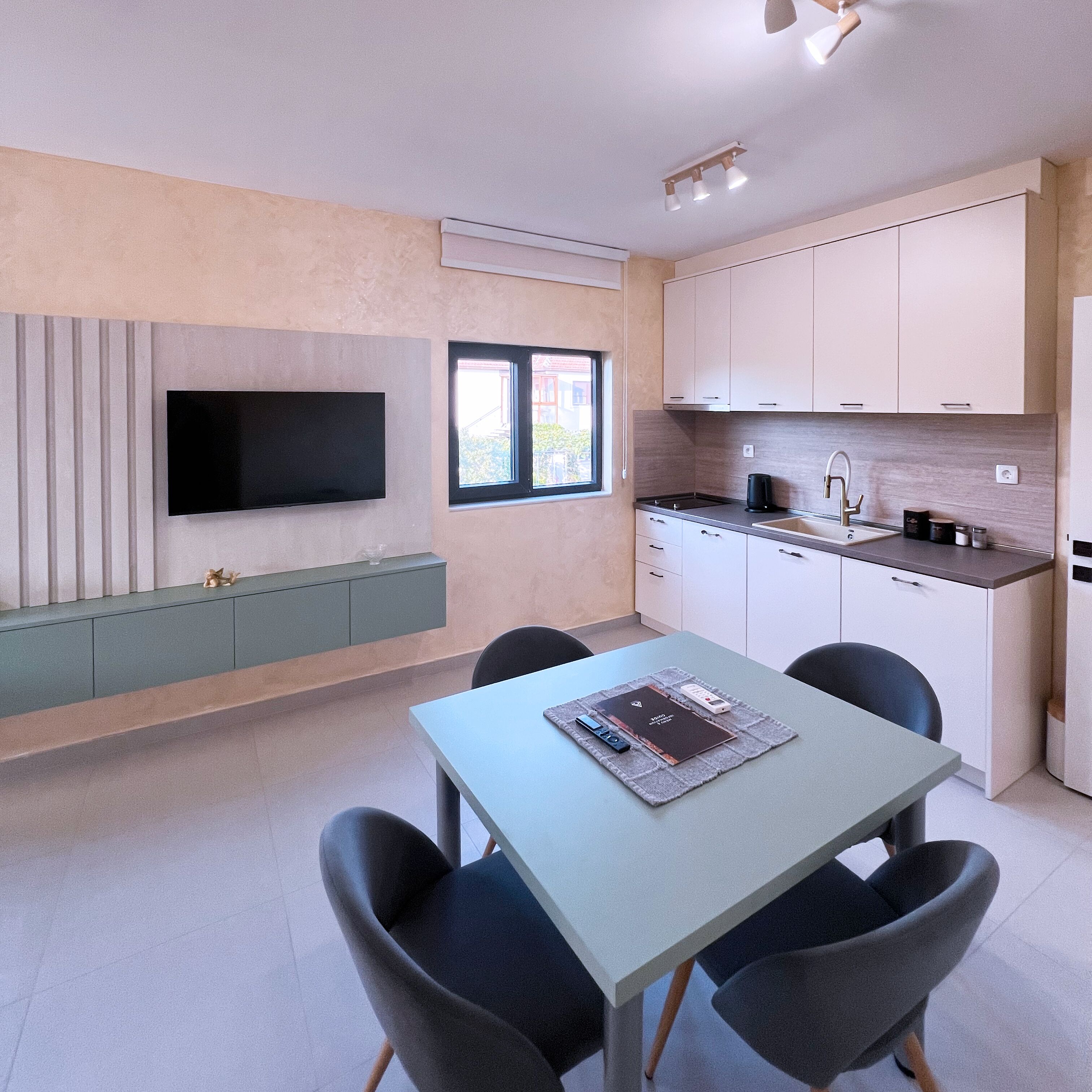 Een moderne keuken met een inbouwfornuis, een spoelbak en een flatscreen televisie aan de muur.