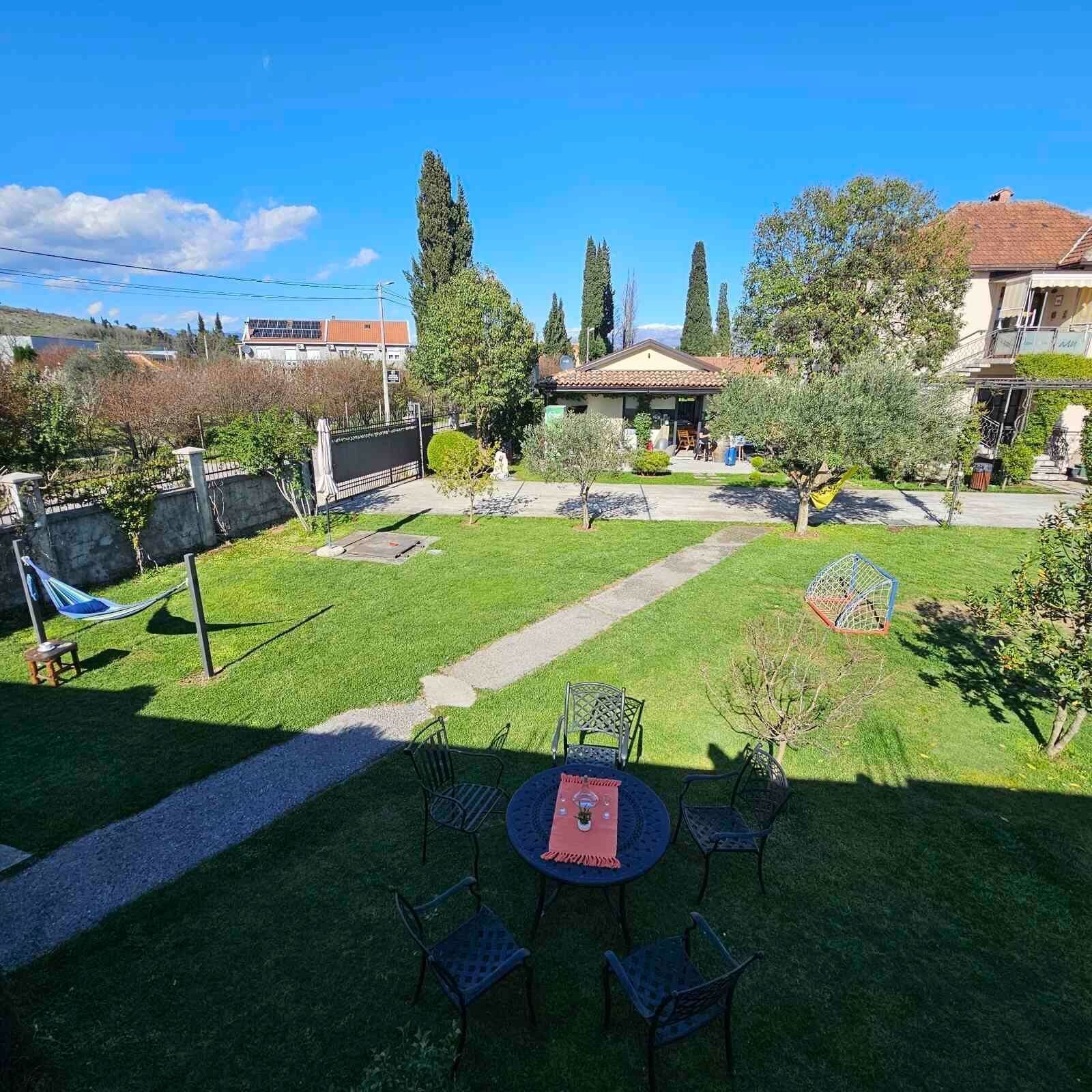 A backyard with a dining area, a hammock, and a small garden.