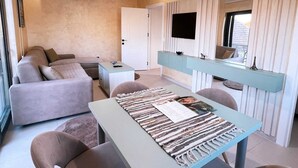 A modern living room with a sofa, a coffee table, and a TV mounted on the wall. - Apartments Aerodrom (Podgorica)