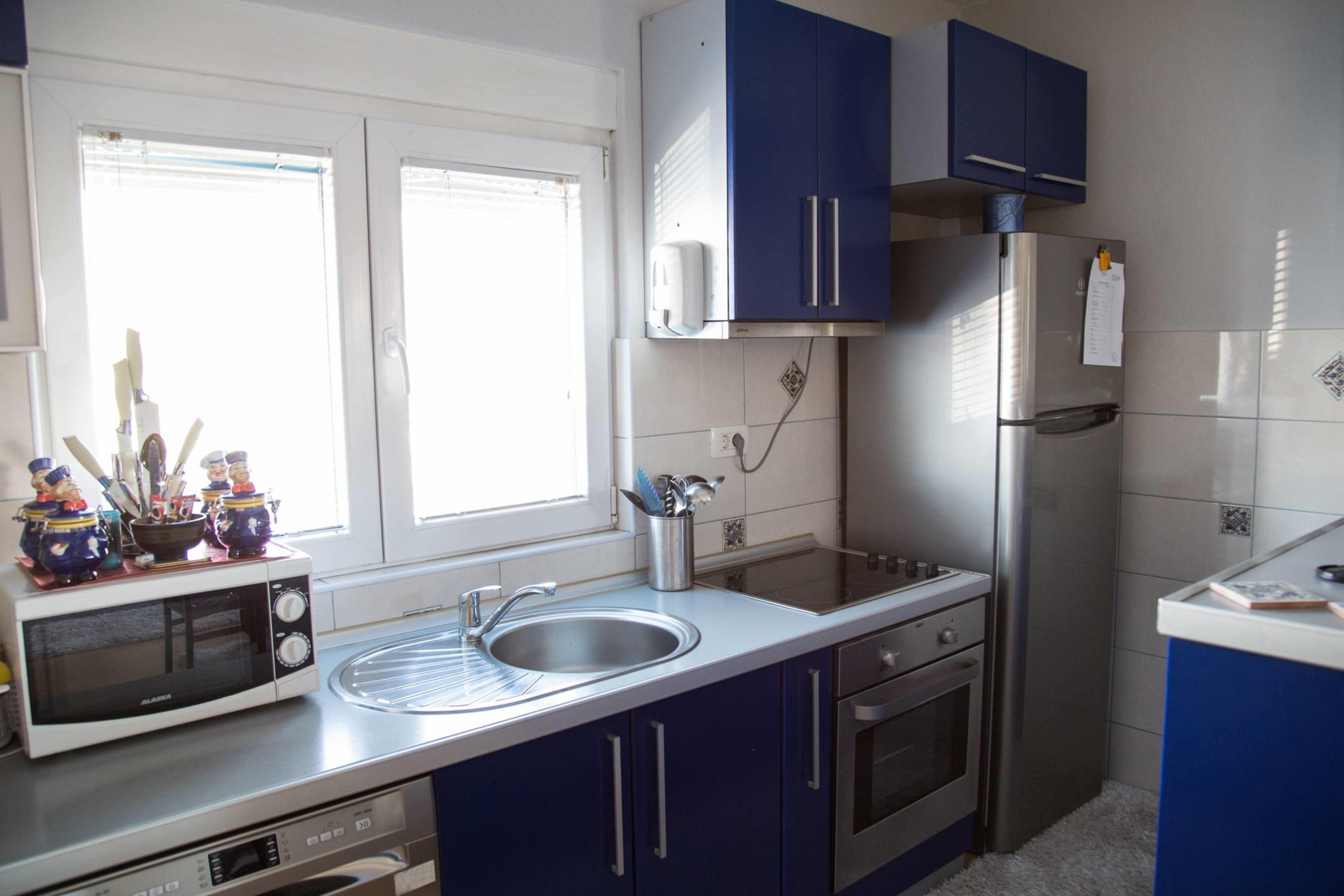 A kitchen with a microwave, sink, cabinets, and a refrigerator.