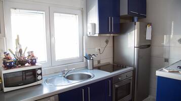 A kitchen with a microwave, sink, cabinets, and a refrigerator.