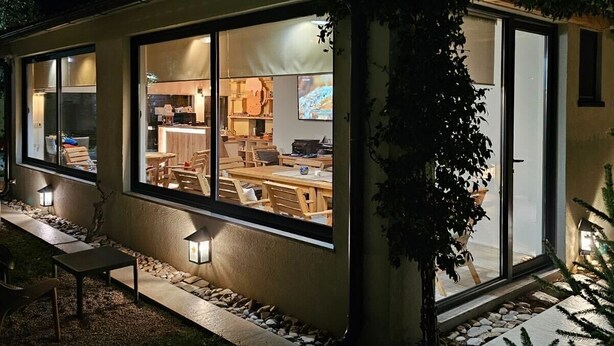 A modern house with large windows, a visible kitchen area, and outdoor seating. - Apartments Aerodrom (Podgorica)