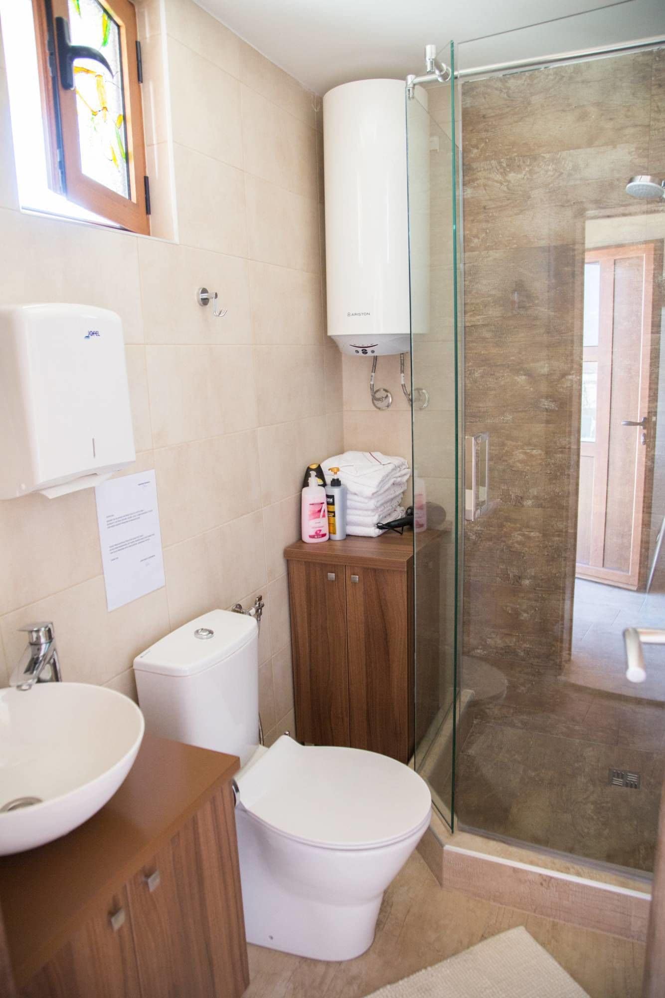 A modern bathroom with a glass shower enclosure, a white toilet, a sink, and a wooden cabinet.
