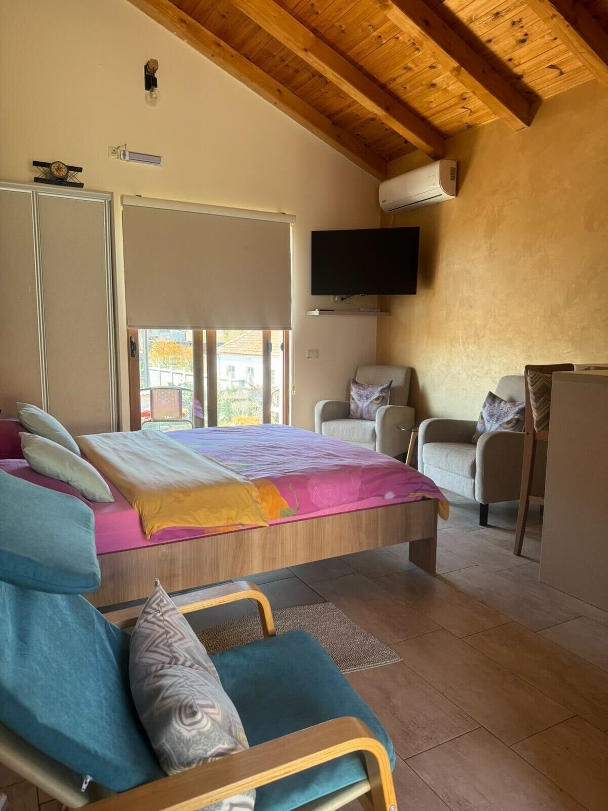 Une chambre à coucher avec un lit, une télévision, une chaise et un canapé.