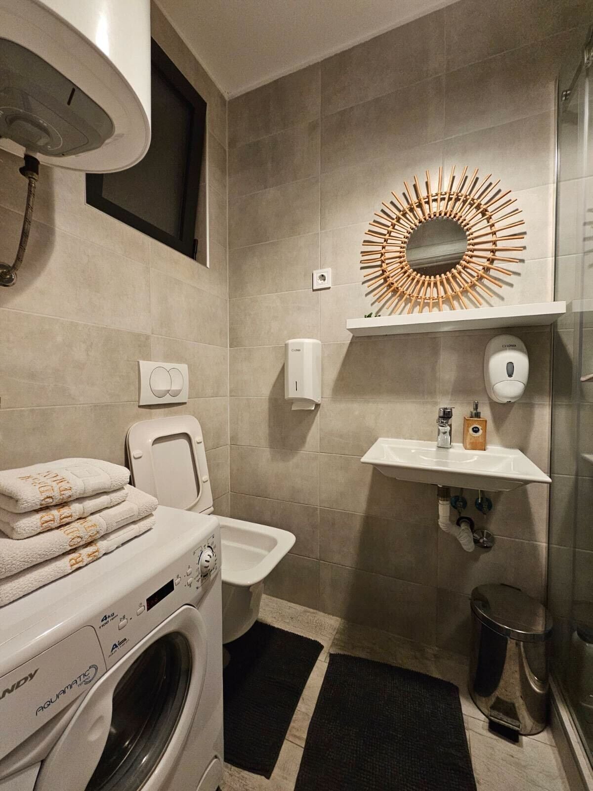 Ein modernes Badezimmer mit Waschmaschine, Toilette, Waschbecken und einem dekorativen Spiegel.