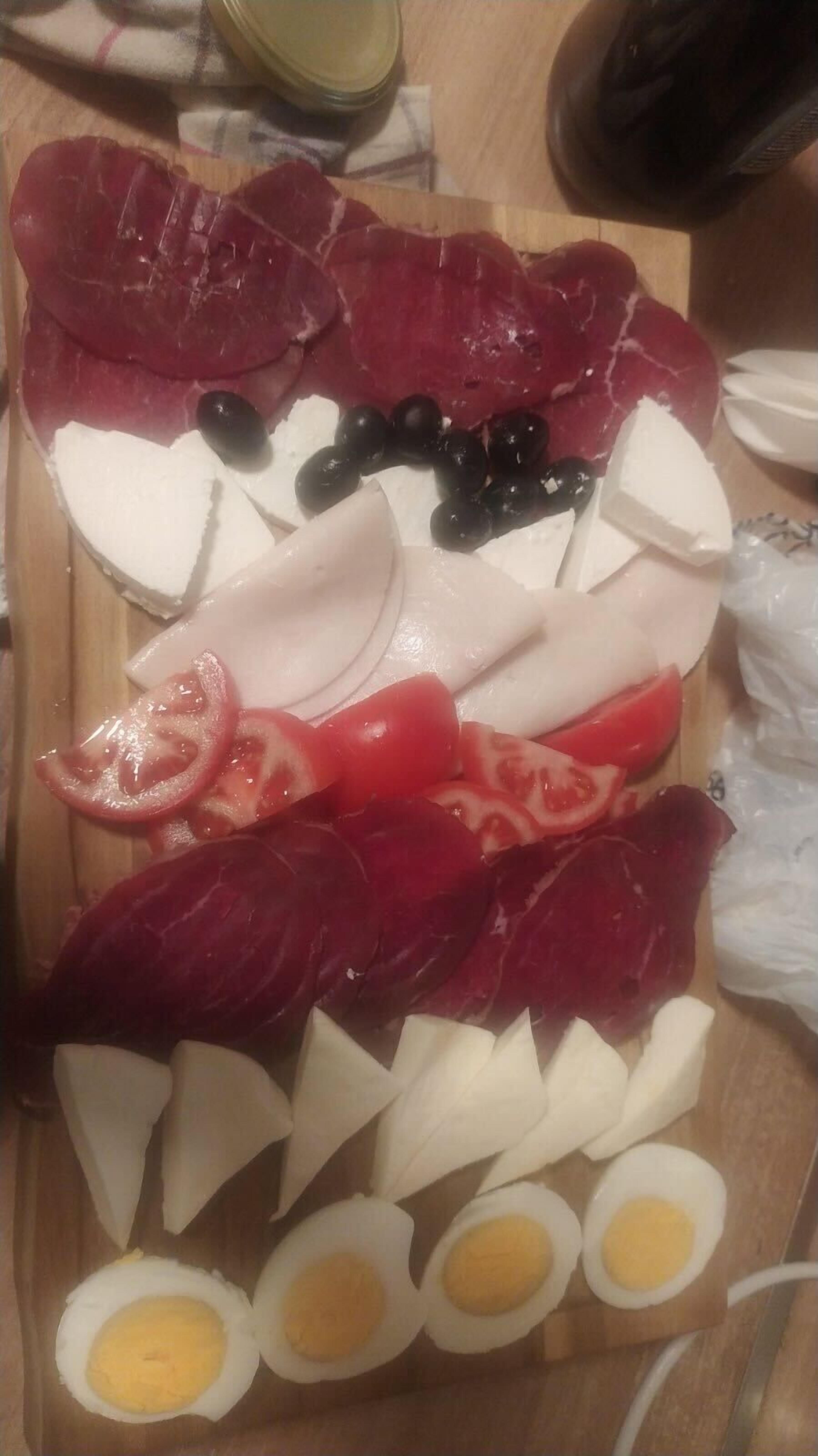 A charcuterie board with various meats, cheeses, and fruits.