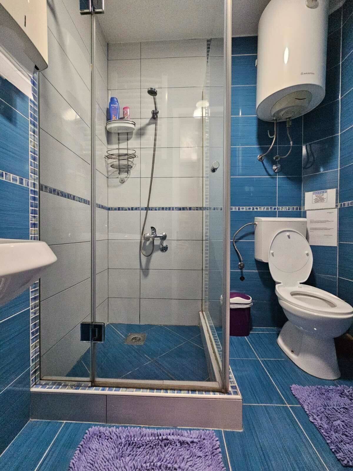 A modern bathroom with a glass-enclosed shower, a toilet, and a sink.