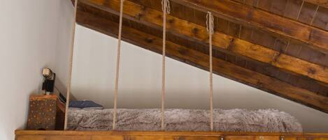 Un dormitorio estilo loft con techo de madera y vigas a la vista.