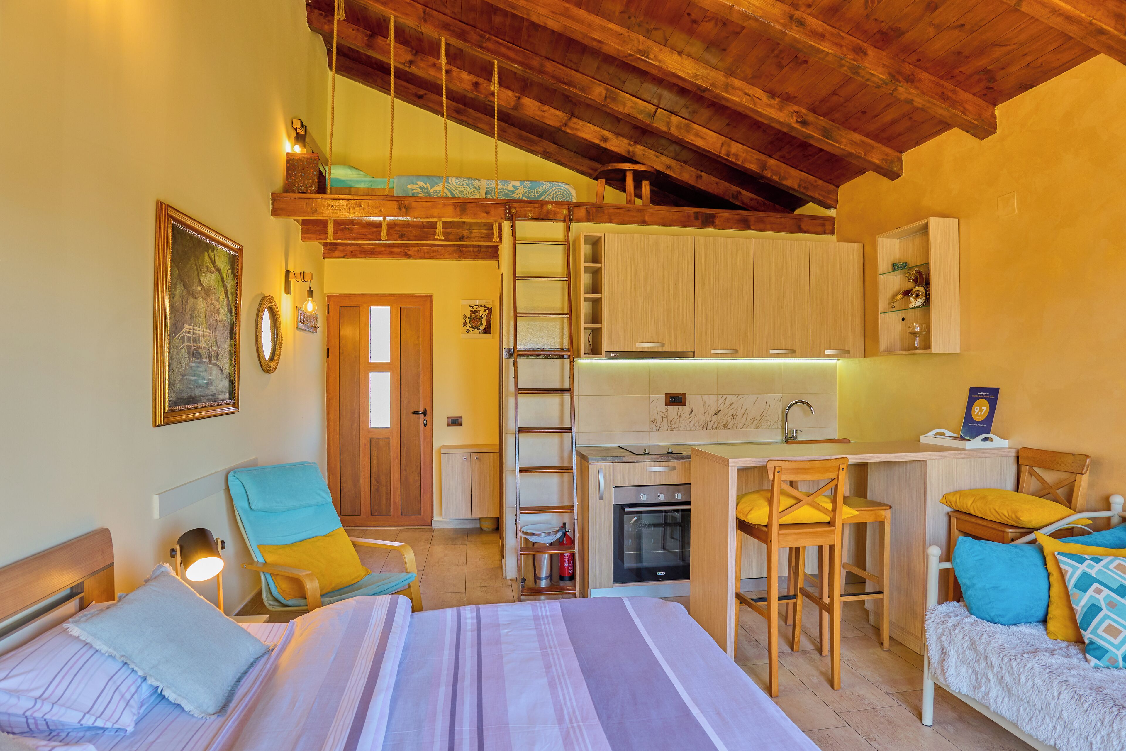 A compact room with a bed, a desk, a chair, and a kitchenette.