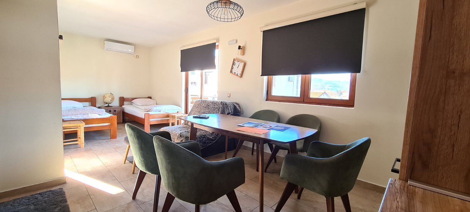 A room with a bed, a table with chairs, a sofa, and a window with a blind.