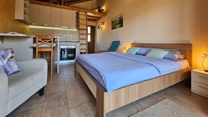 A cozy bedroom with a wooden ceiling, a bed with blue bedding, a nightstand, and a chair. - Apartments Aerodrom (Podgorica)