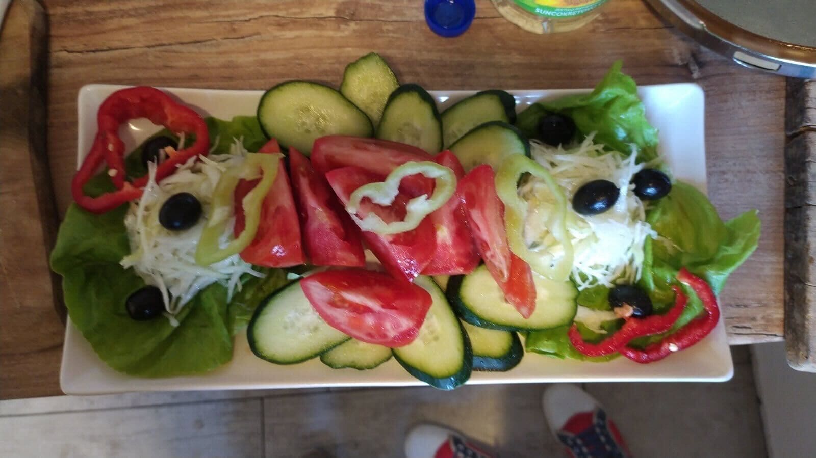 A plate of salad with cucumbers, tomatoes, lettuce, and olives.