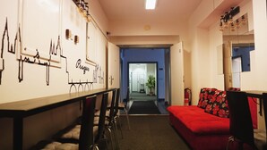 A hotel room with a dining area, a red sofa, and a wall with a Prague cityscape mural. - Hostel and Apartment Blue88 (Prague)