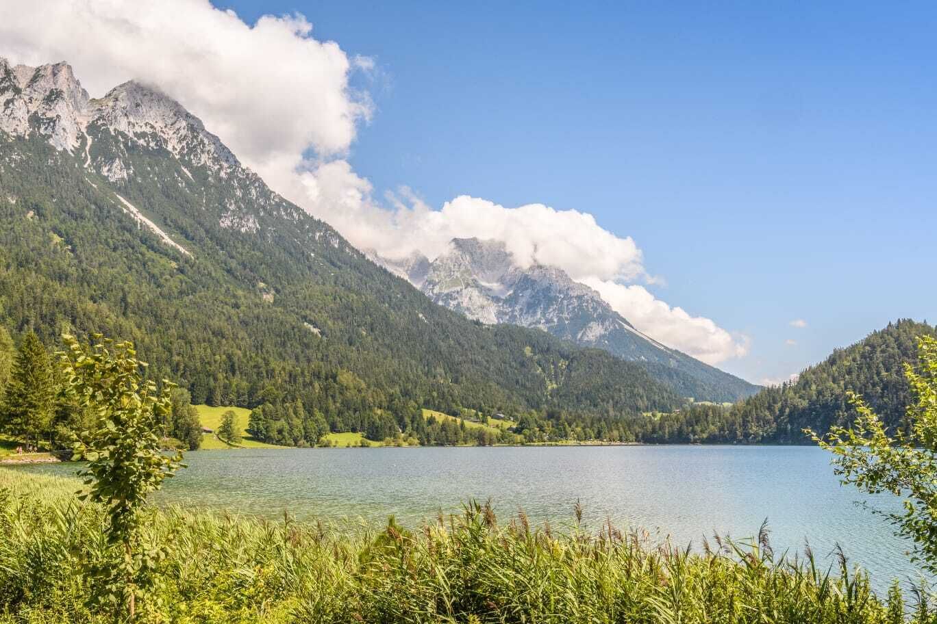 A mountain landscape with a lake and forested hills.