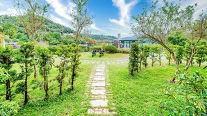 A garden pathway leading to a building with a view of a hill and a bridge in the distance. - I Love You Homestay (Yuchi)