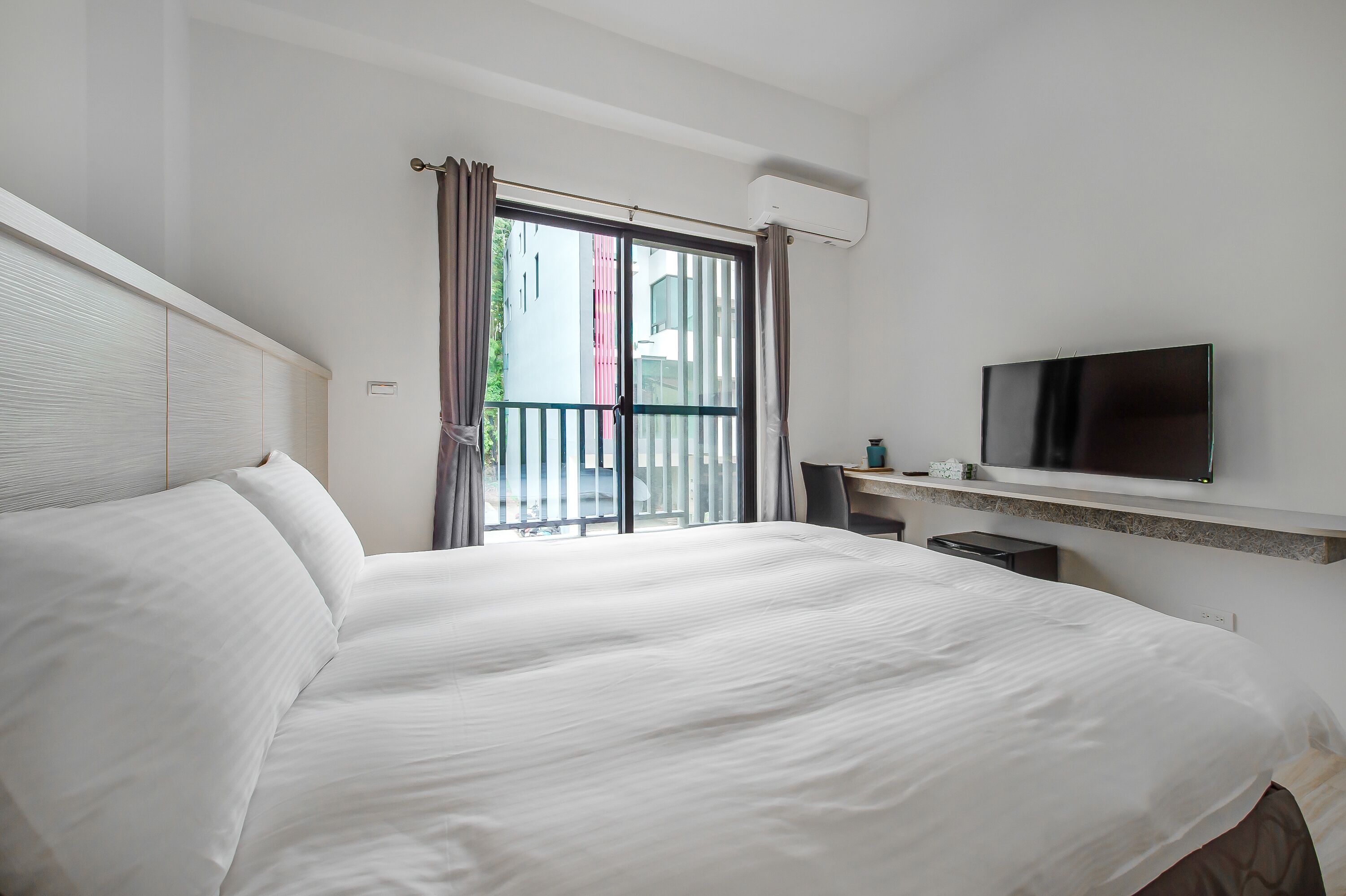 Une chambre d’hôtel avec un grand lit, un bureau, une télévision et une vue sur l’extérieur.