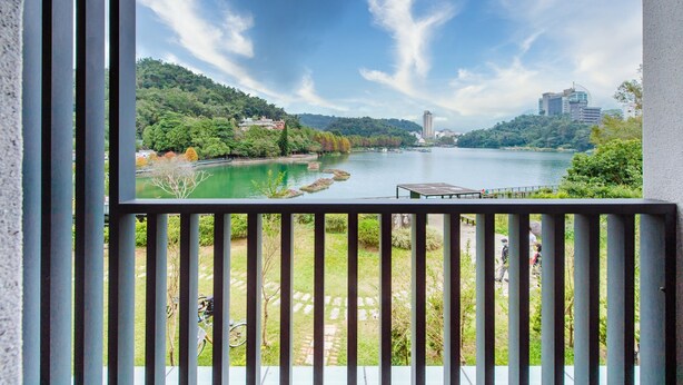 A view from a balcony with a railing, overlooking a river, a bridge, and buildings in the distance. - I Love You Homestay (Yuchi)