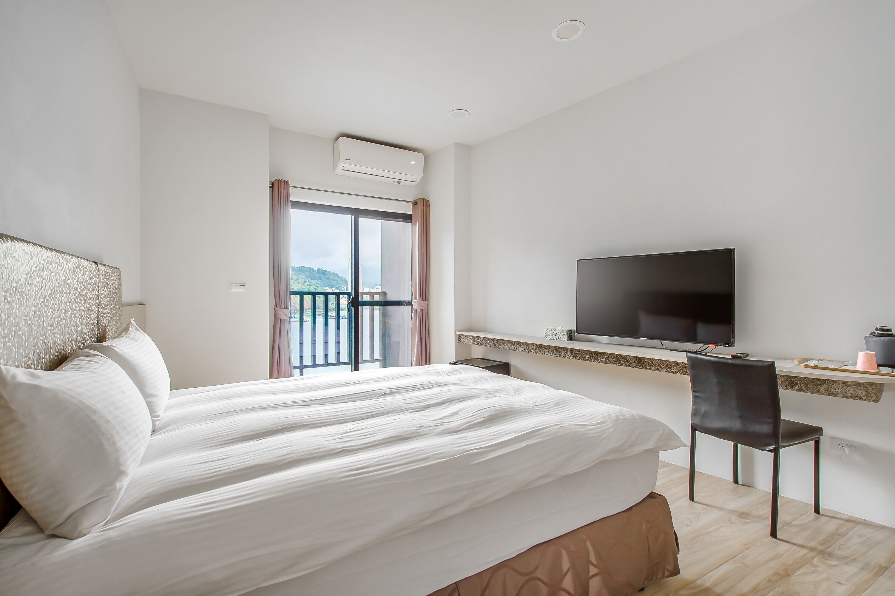 Une chambre d’hôtel comprenant un lit, un bureau avec une chaise, une télévision et un balcon avec vue.