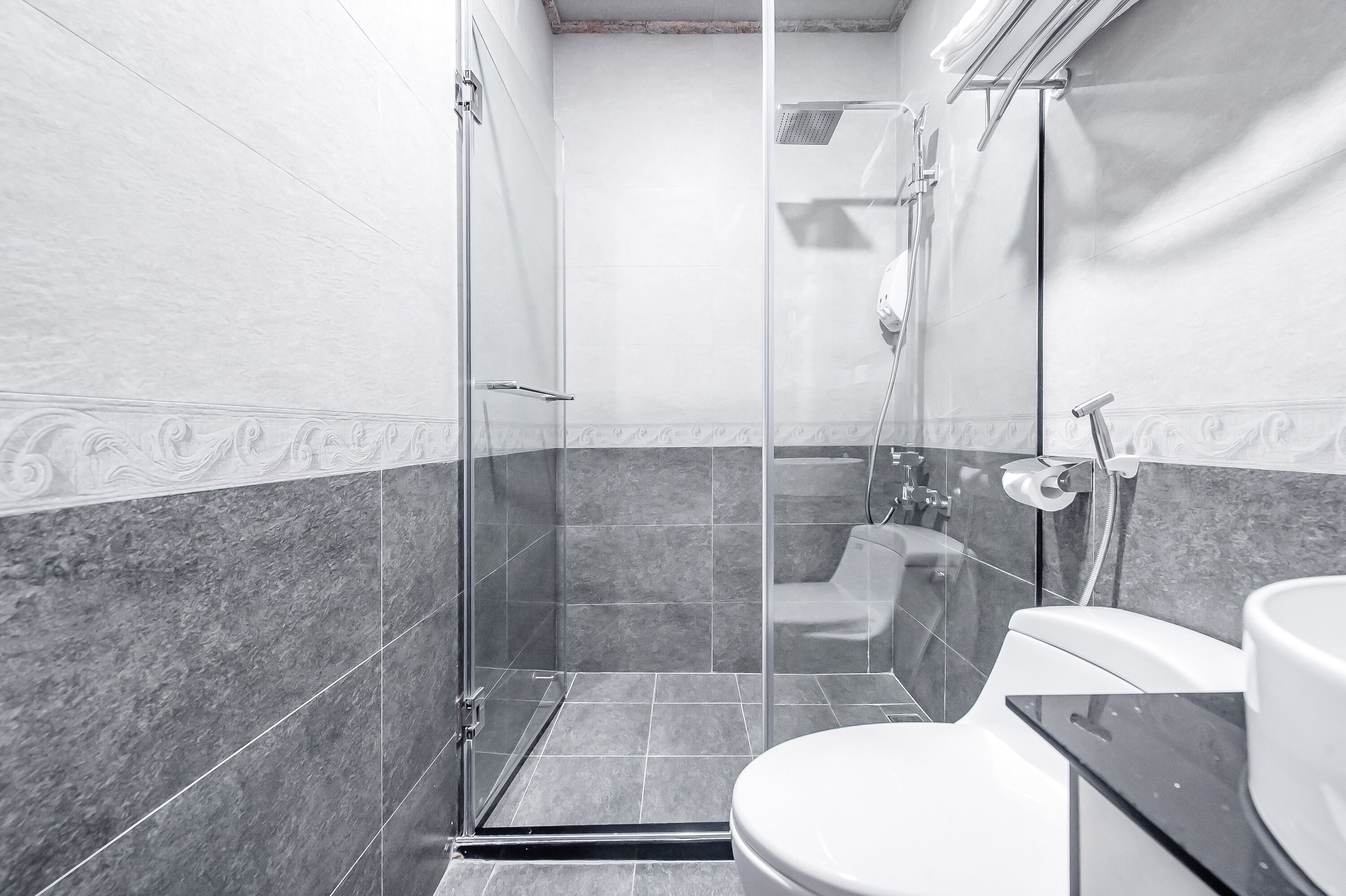 A modern bathroom with a glass-enclosed shower, a toilet, and a sink.