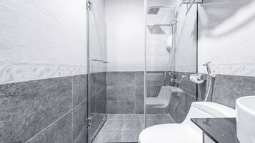 A modern bathroom with a glass-enclosed shower, a toilet, and a sink.