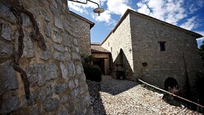 Un edificio de piedra con un camino adoquinado, una farola rústica y un cielo azul despejado.