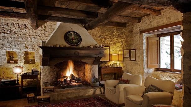 Una habitación acogedora con chimenea de piedra, vigas de madera y un ventanal grande.
