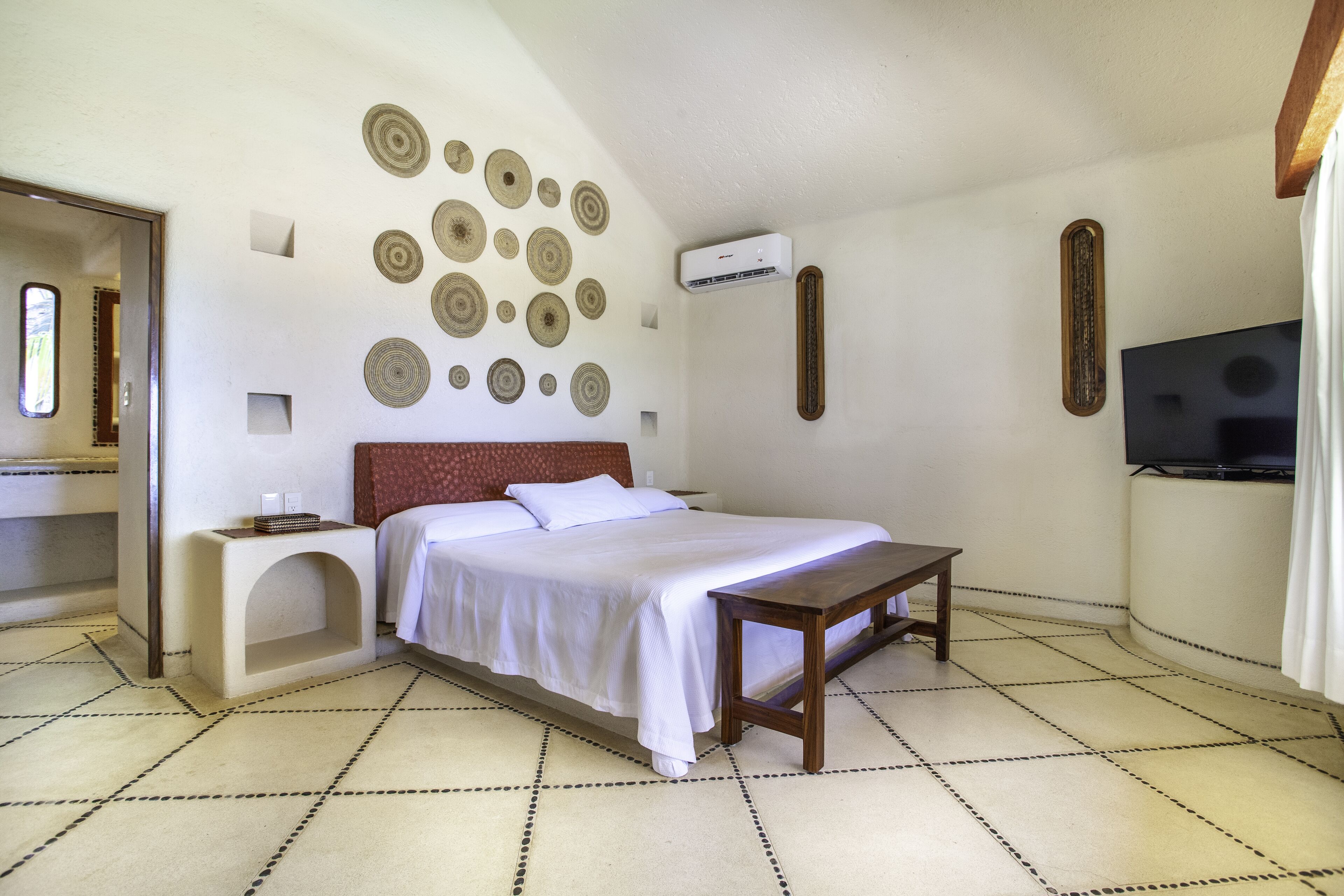 A bedroom with a bed, bedside table, wall decor, and a television.