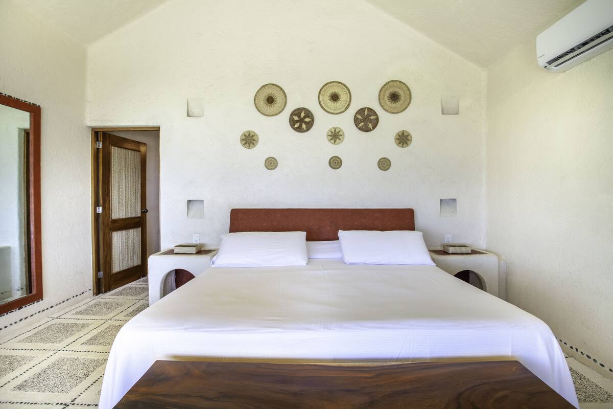 Habitación de hotel con una cama grande, dos mesitas de noche, un cabecero de madera y decoración en la pared.