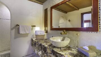A bathroom with a stone countertop, a large bowl sink, a mirror, and a towel rack.