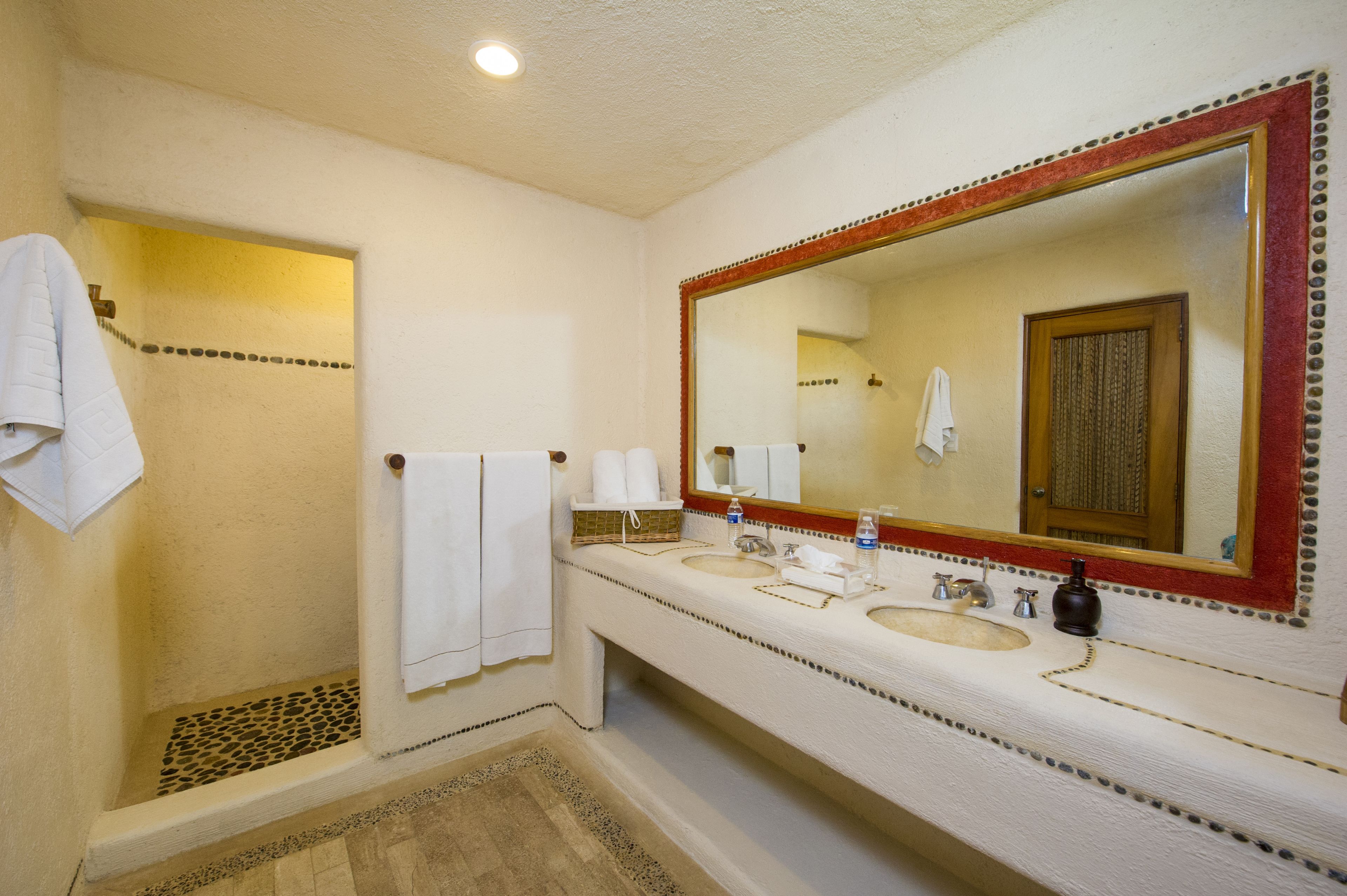 A bathroom with a shower, two sinks, a large mirror, and towels.