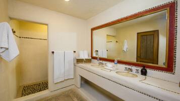 A bathroom with a shower, two sinks, a large mirror, and towels.