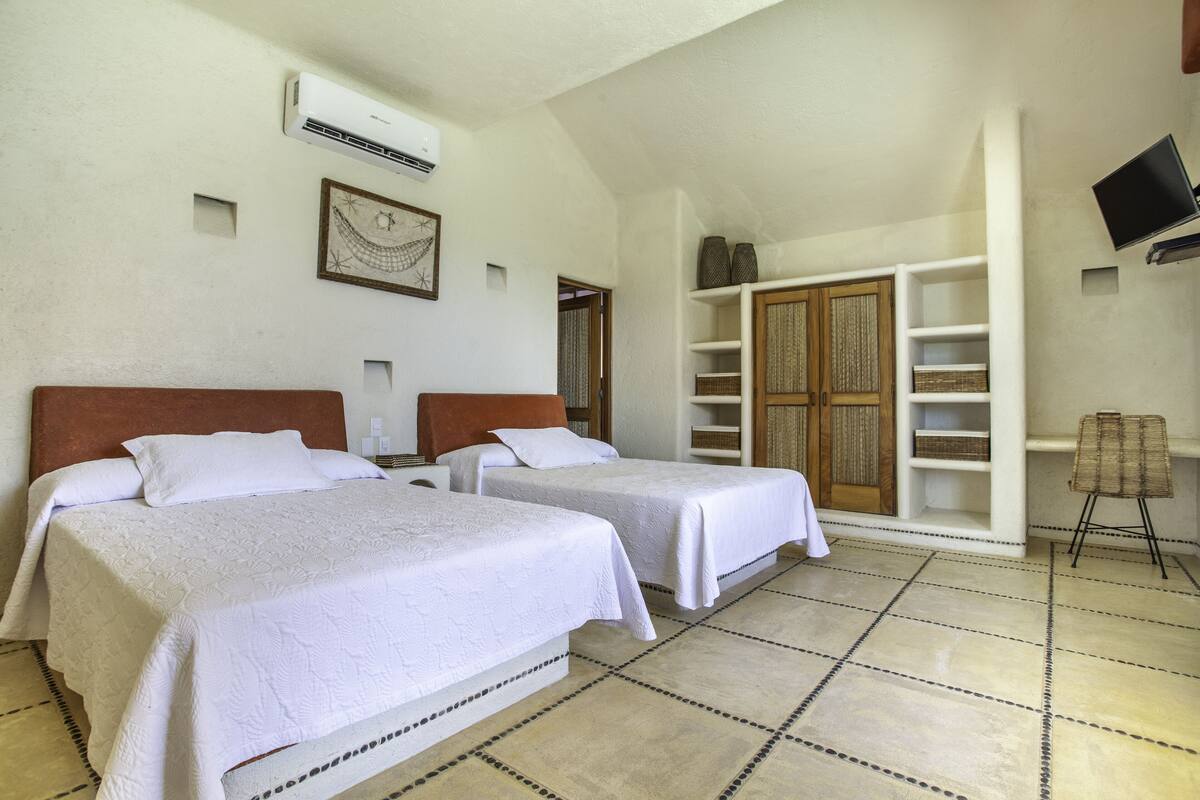 Habitación de hotel con dos camas, televisión y un armario grande.
