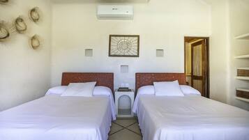 Habitación de hotel con dos camas, aire acondicionado instalado en la pared, un adorno mural y una puerta con cortina.